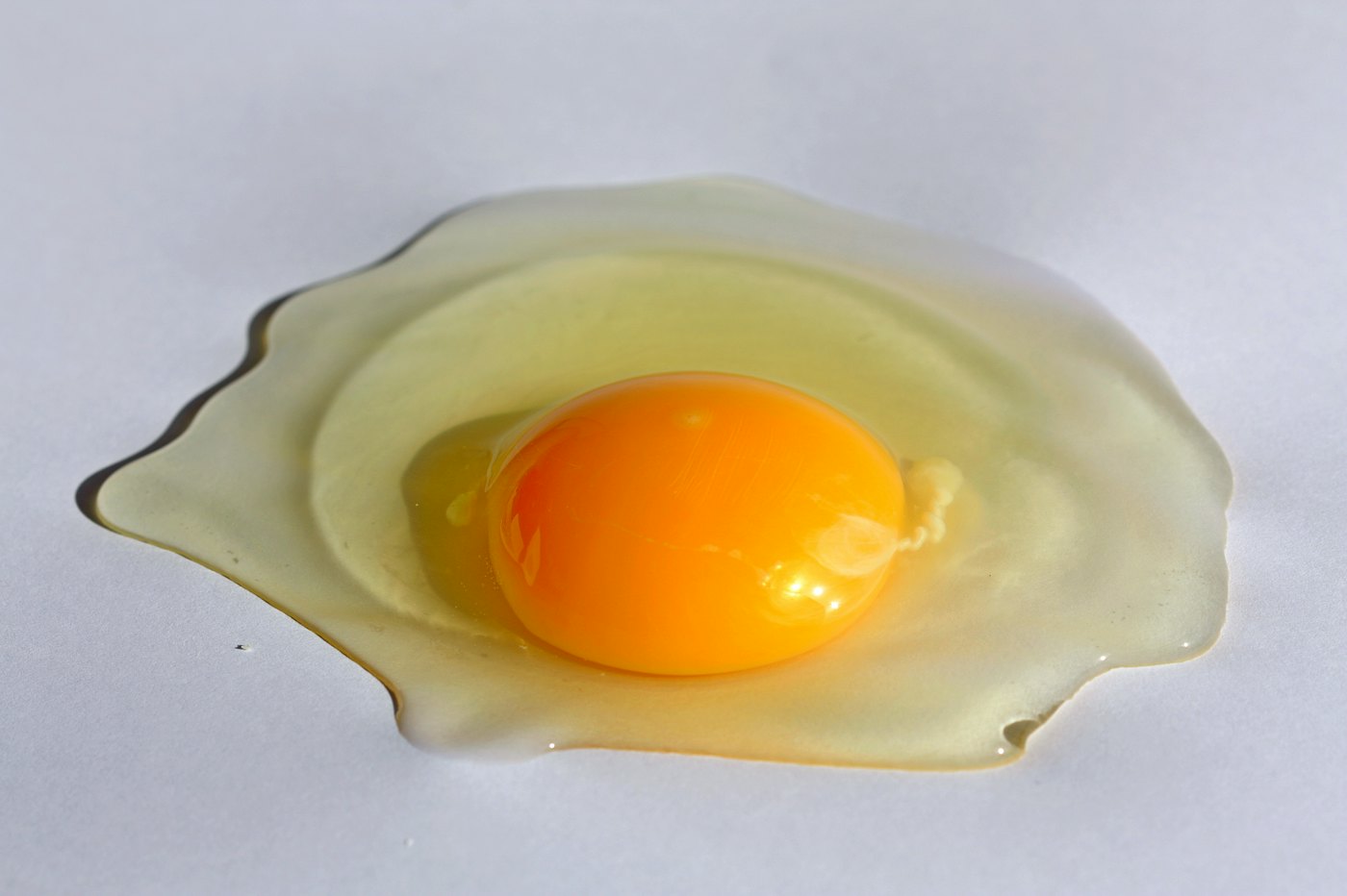 A cracked egg with a bright orange yolk