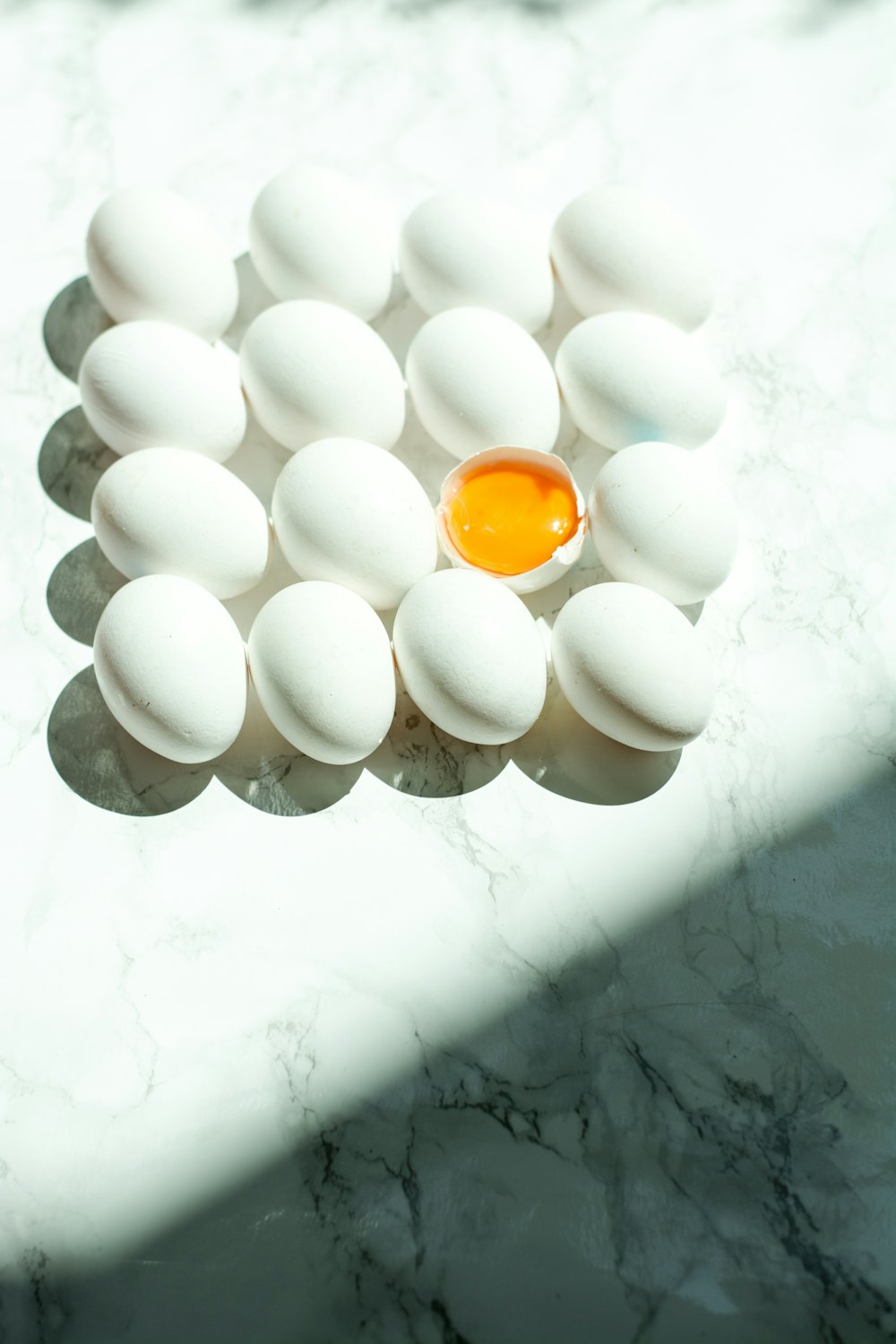 White eggs arranged on a marble surface with one cracked open