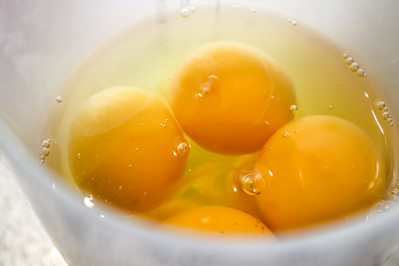 Raw egg yolks in a clear bowl of liquid egg